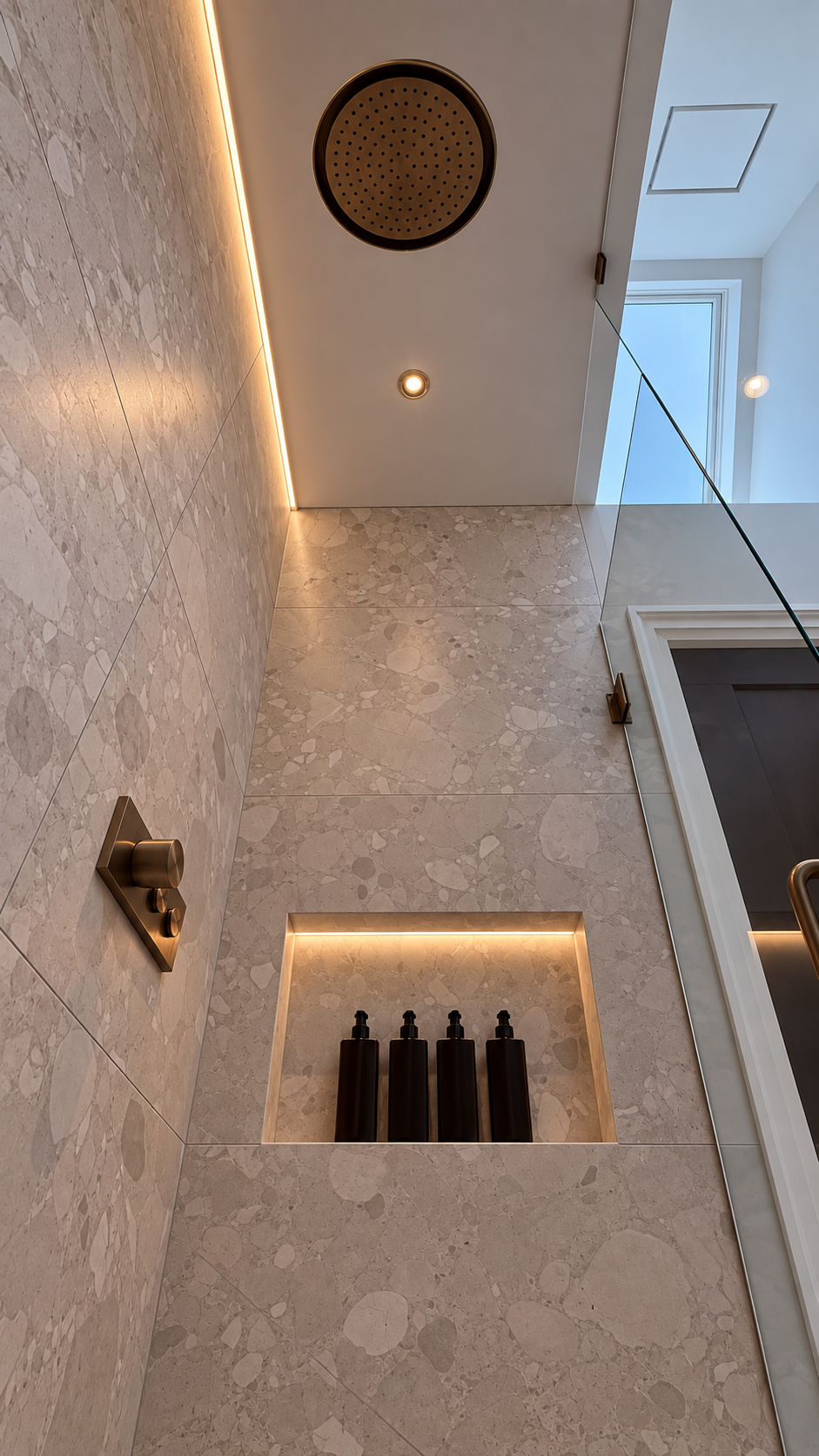 A shower renovation with a recessed wall niche, accent lighting, and a frameless glass panel.