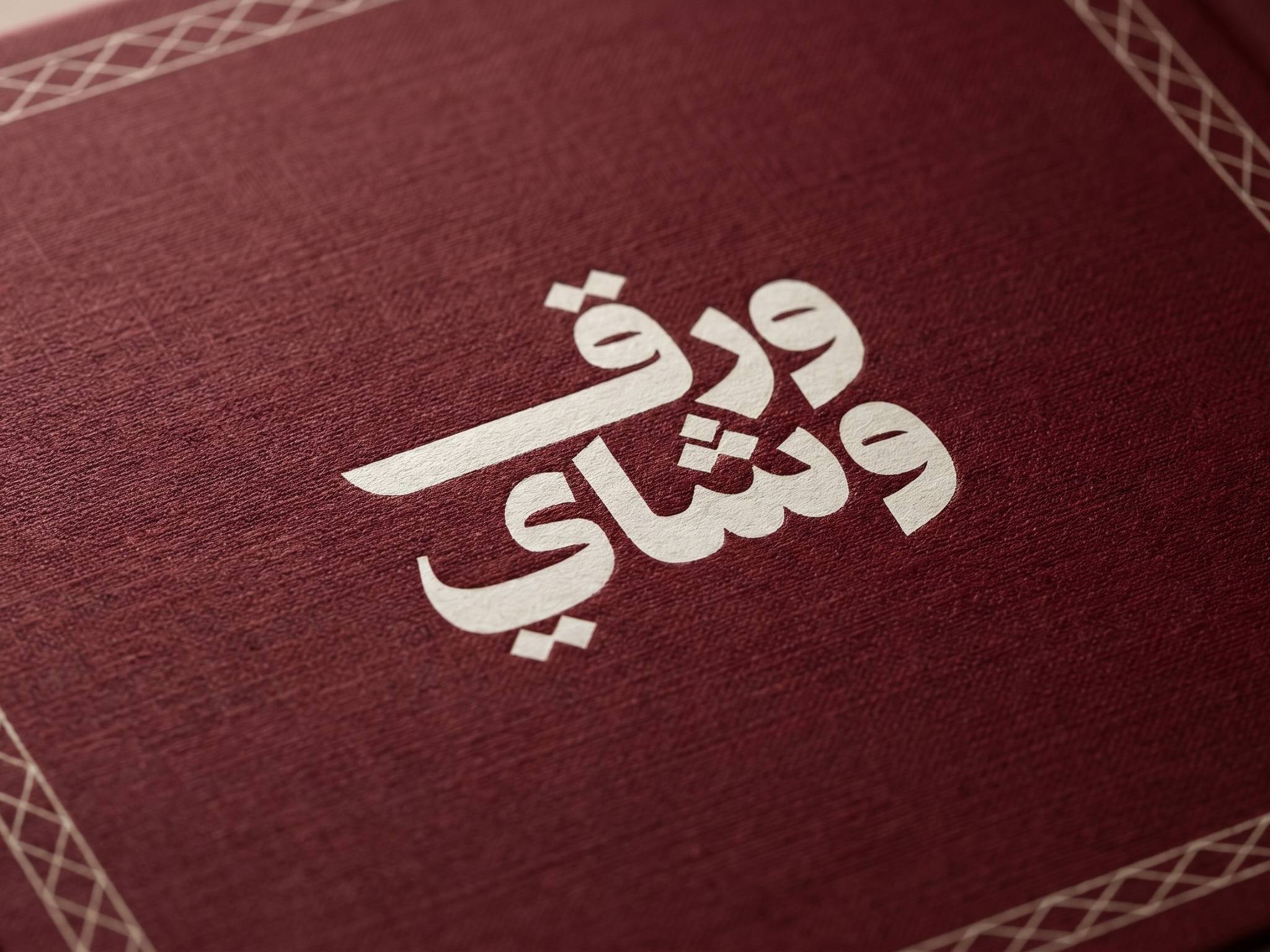 اسم «ورق وشاي» بحروف عربية بيضاء عريضة على خلفية عنابية، مكتوب في سطرين يبدأ كل منهما بحرف واو، ونقاط الحروف معيّنات صغيرة مائلة
