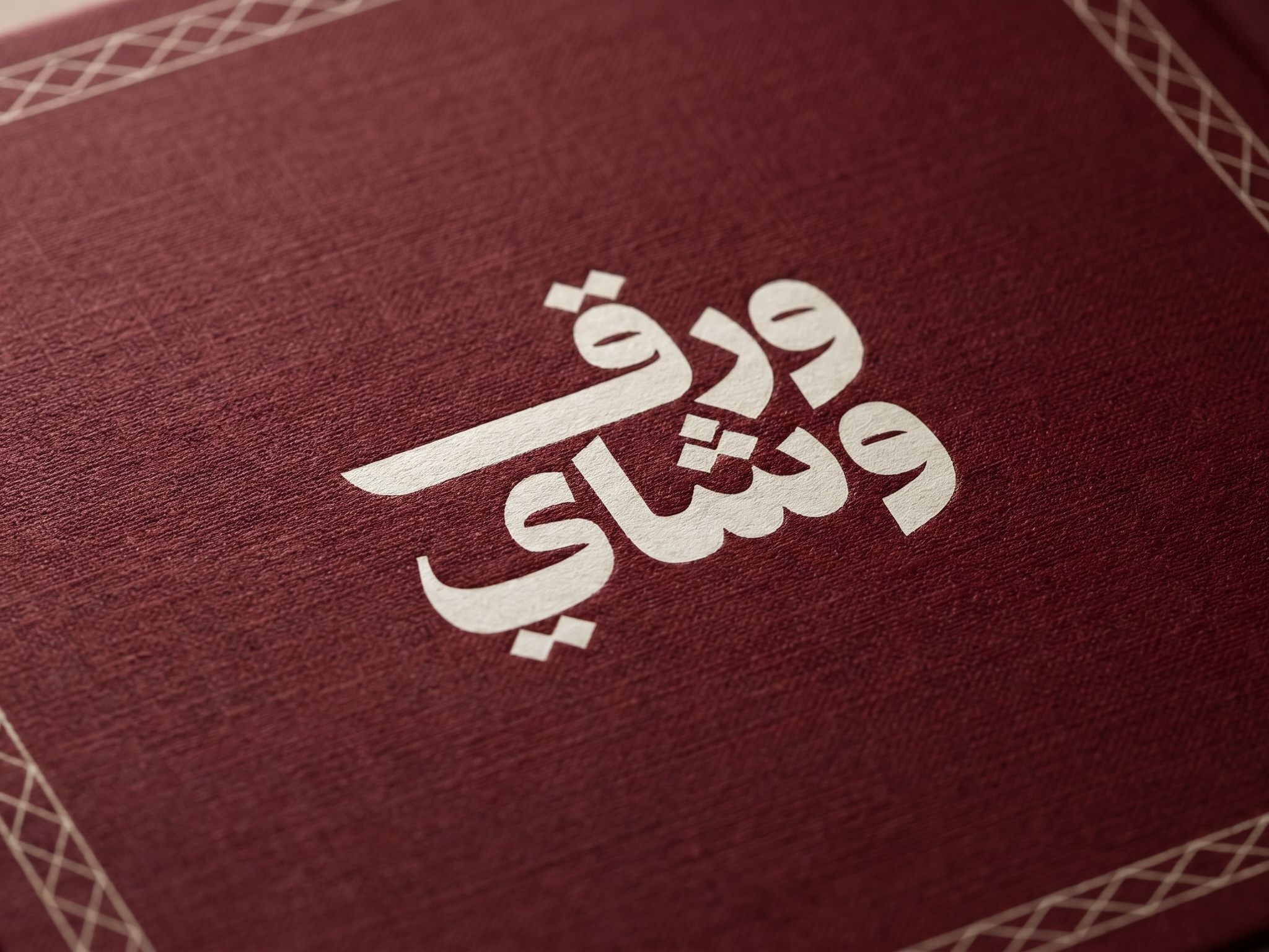 اسم «ورق وشاي» بحروف عربية بيضاء عريضة على خلفية عنابية، مكتوب في سطرين يبدأ كل منهما بحرف واو، ونقاط الحروف معيّنات صغيرة مائلة