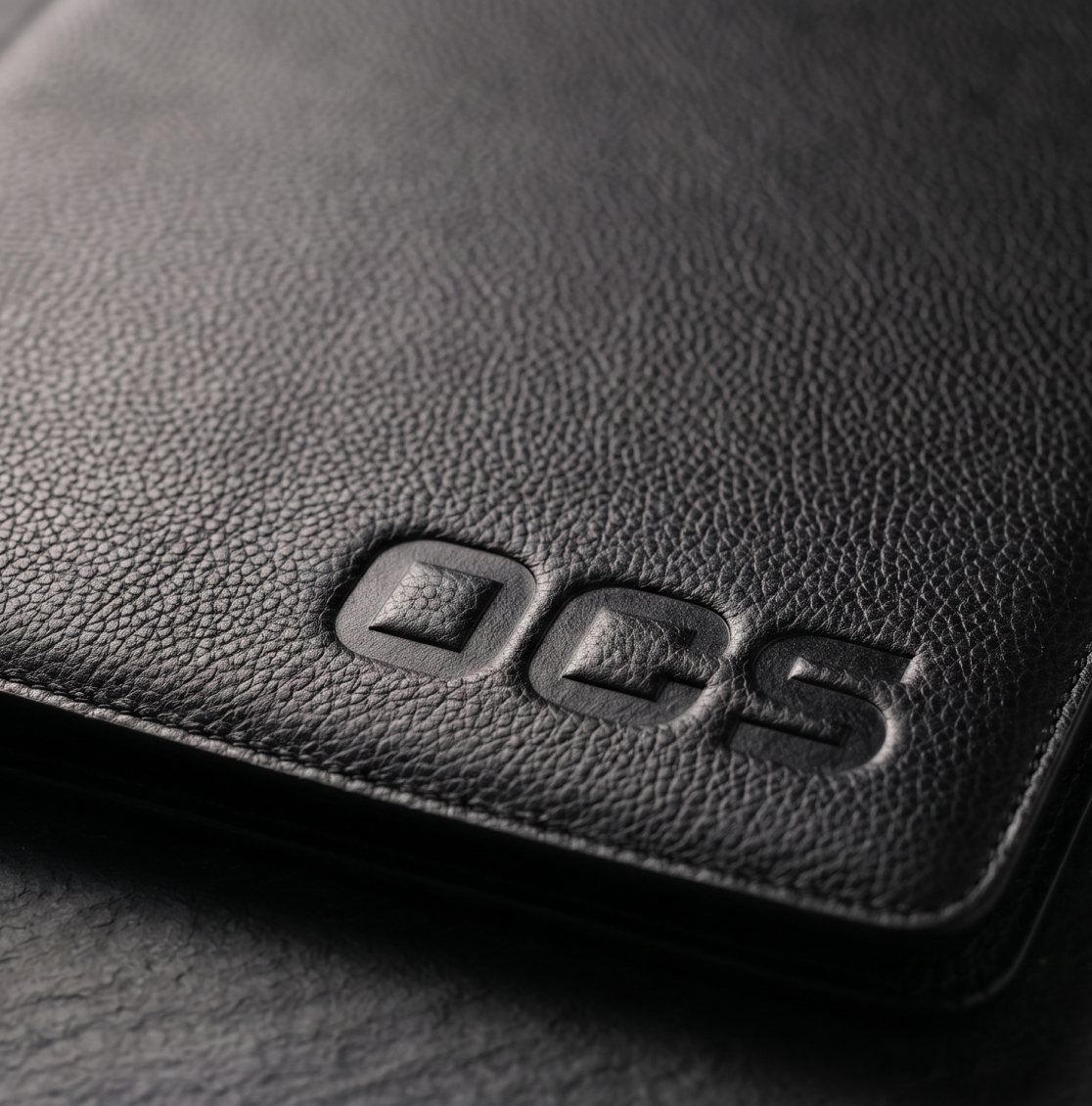 شعار OCS محفوراً على غلاف جلدي أسود