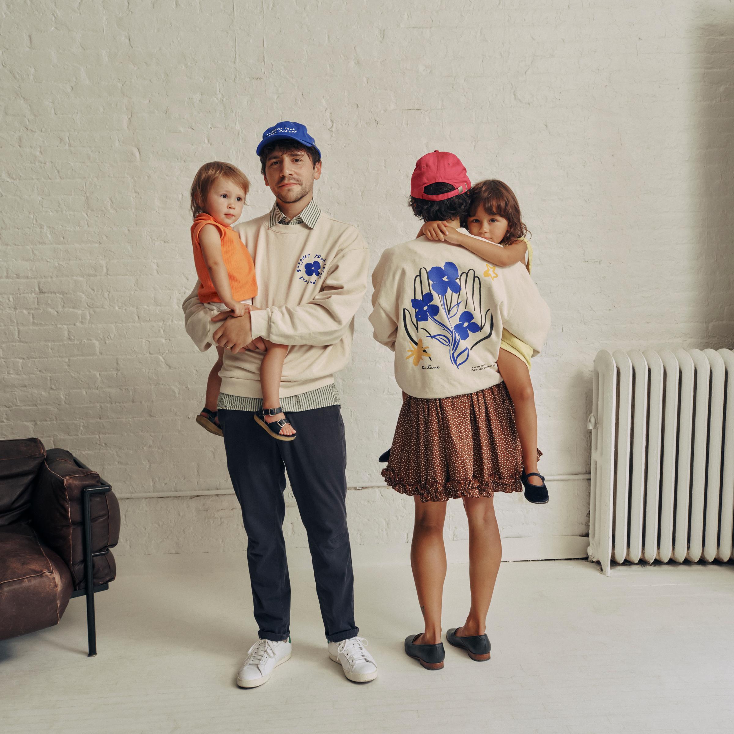 A family shows off the SYLP merch, including the crewneck and the classic cap is blue and berry.
