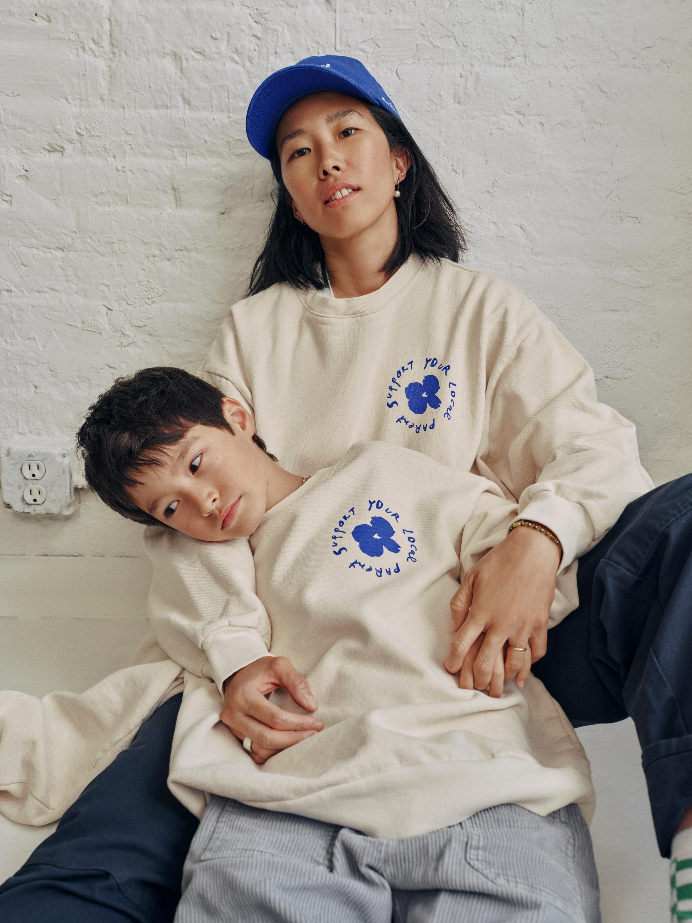 mom and son hold hands while both sporting the SYLP crewneck.