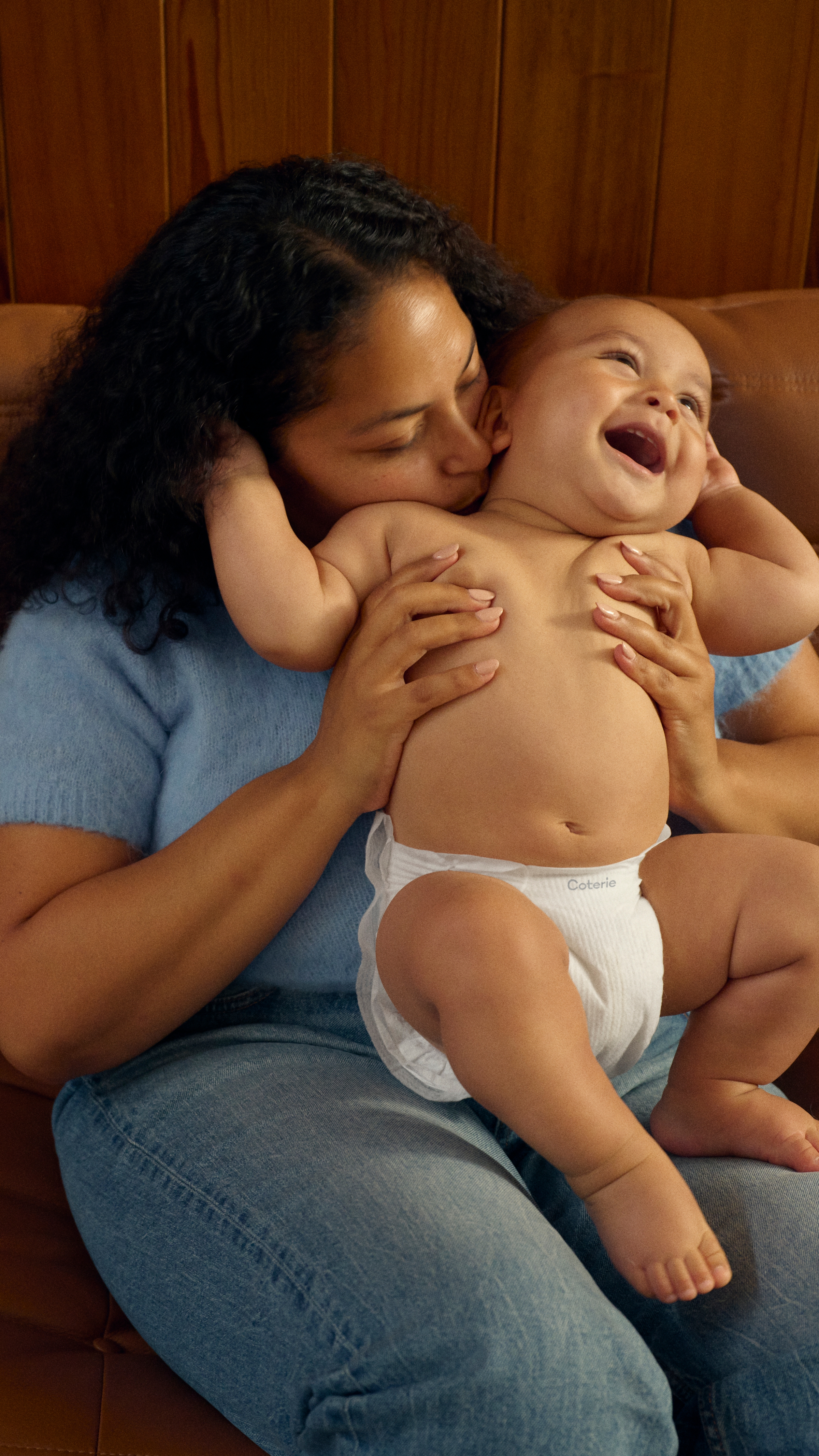 a baby stands up on a couch with the support of his mother and father.