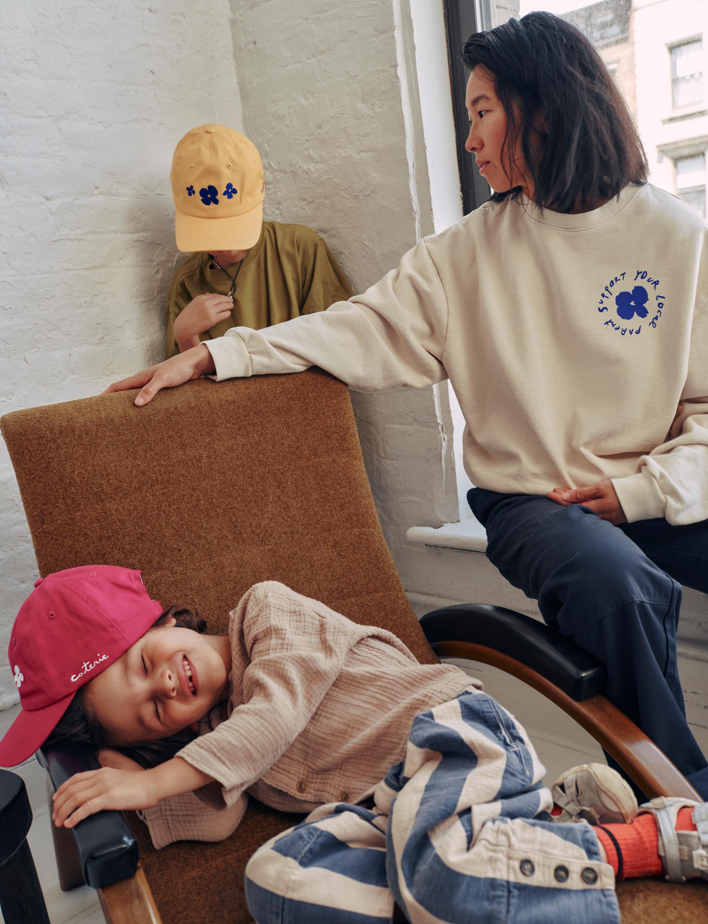 a mother and her kids all sporting SYLP merch, including the crewneck and the hats.