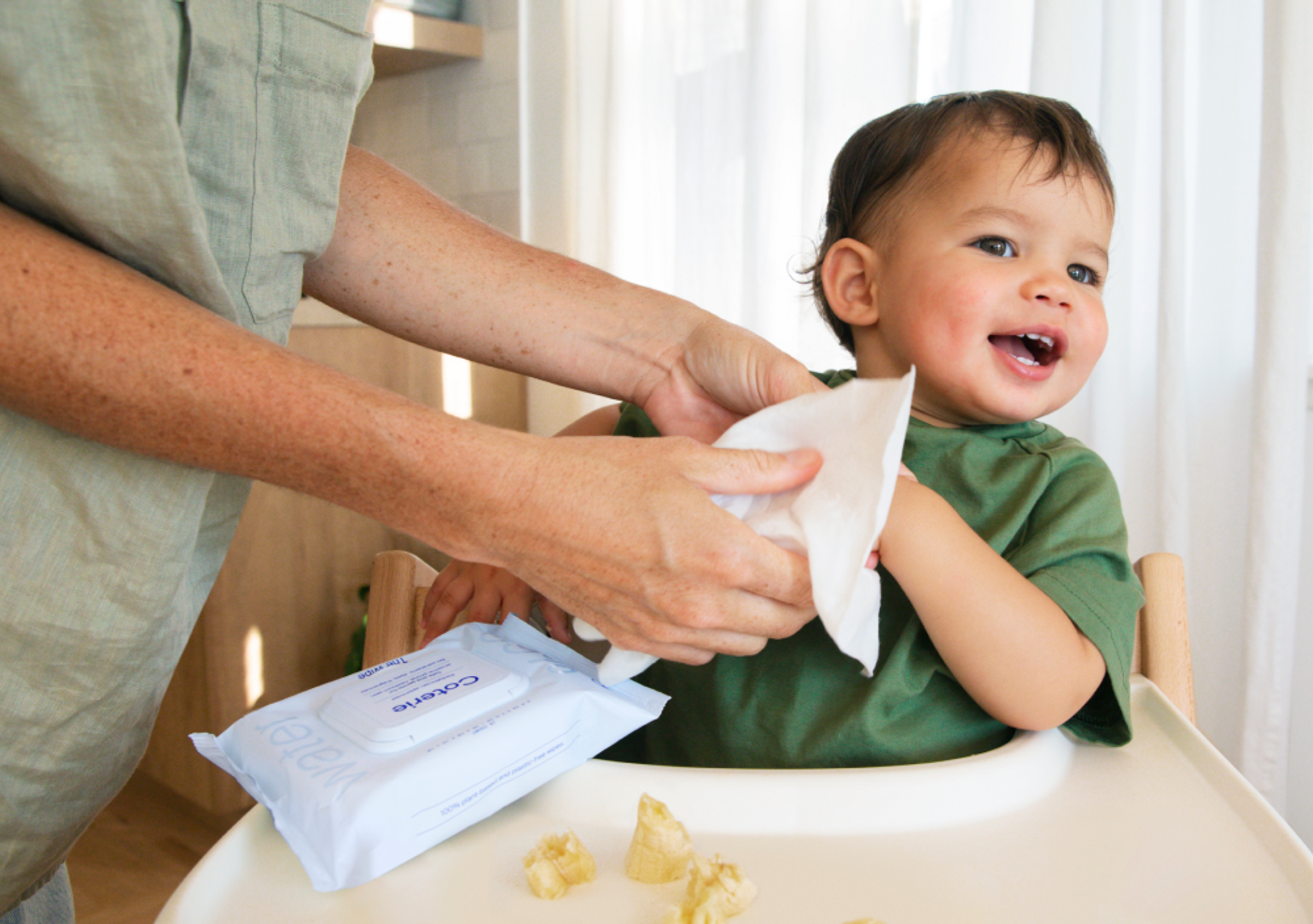 An adult is using a wipe to clean a child after eating