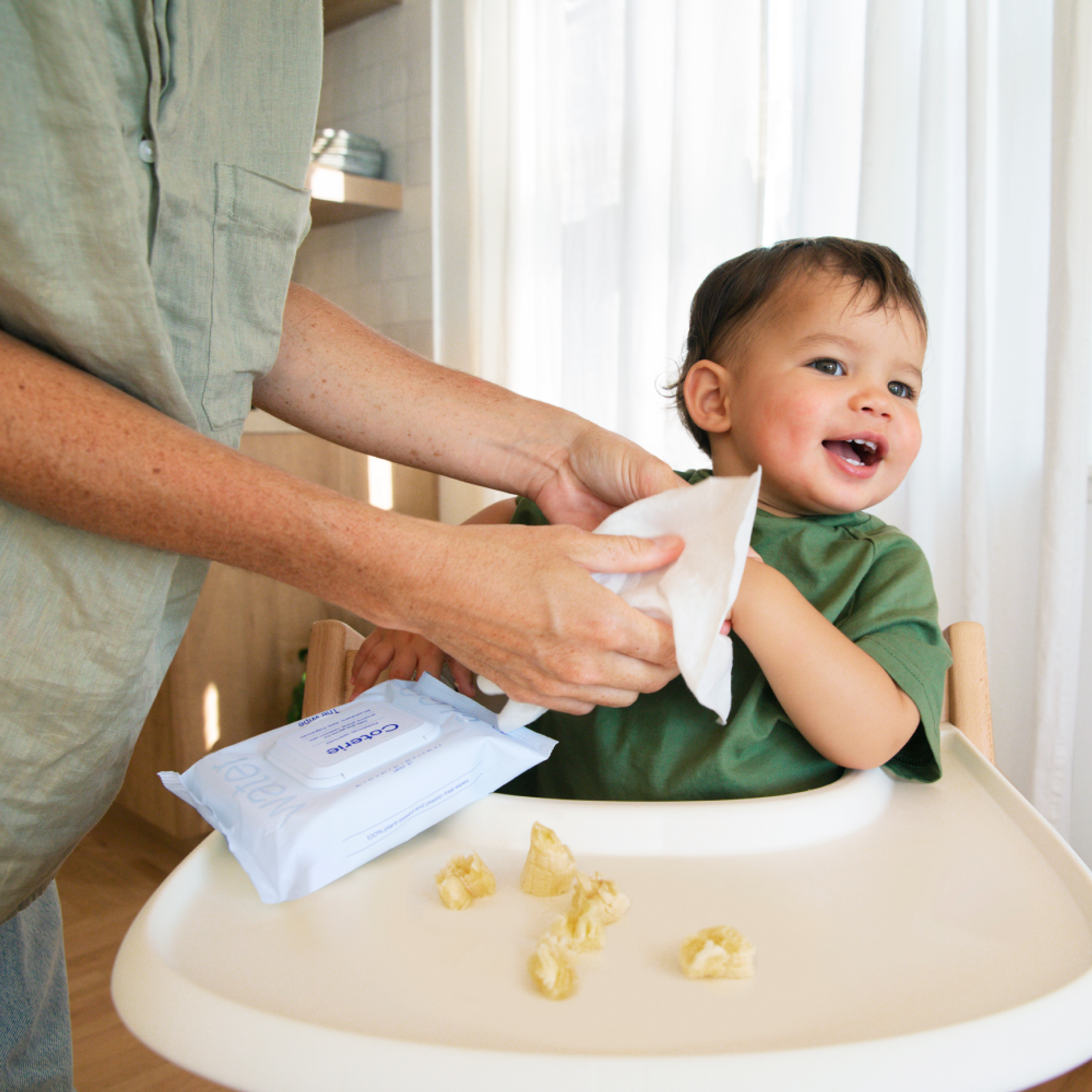 An adult is using a wipe to clean a child after eating
