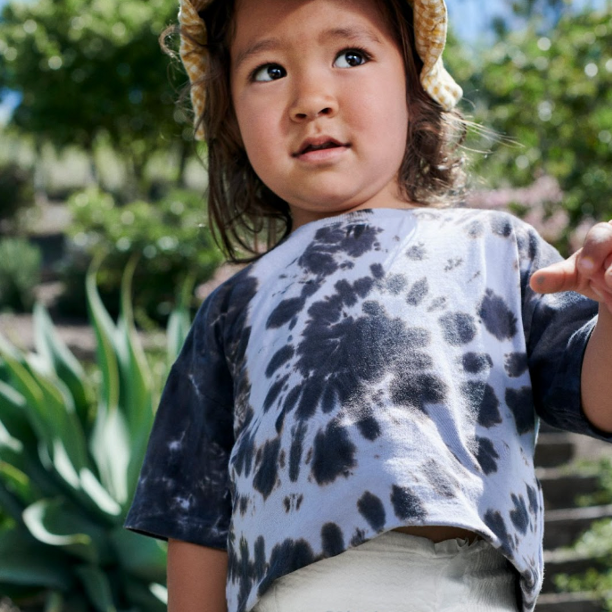 a young boy is seen outside wearing a blue tie-dye shirt and Coterie diaper.