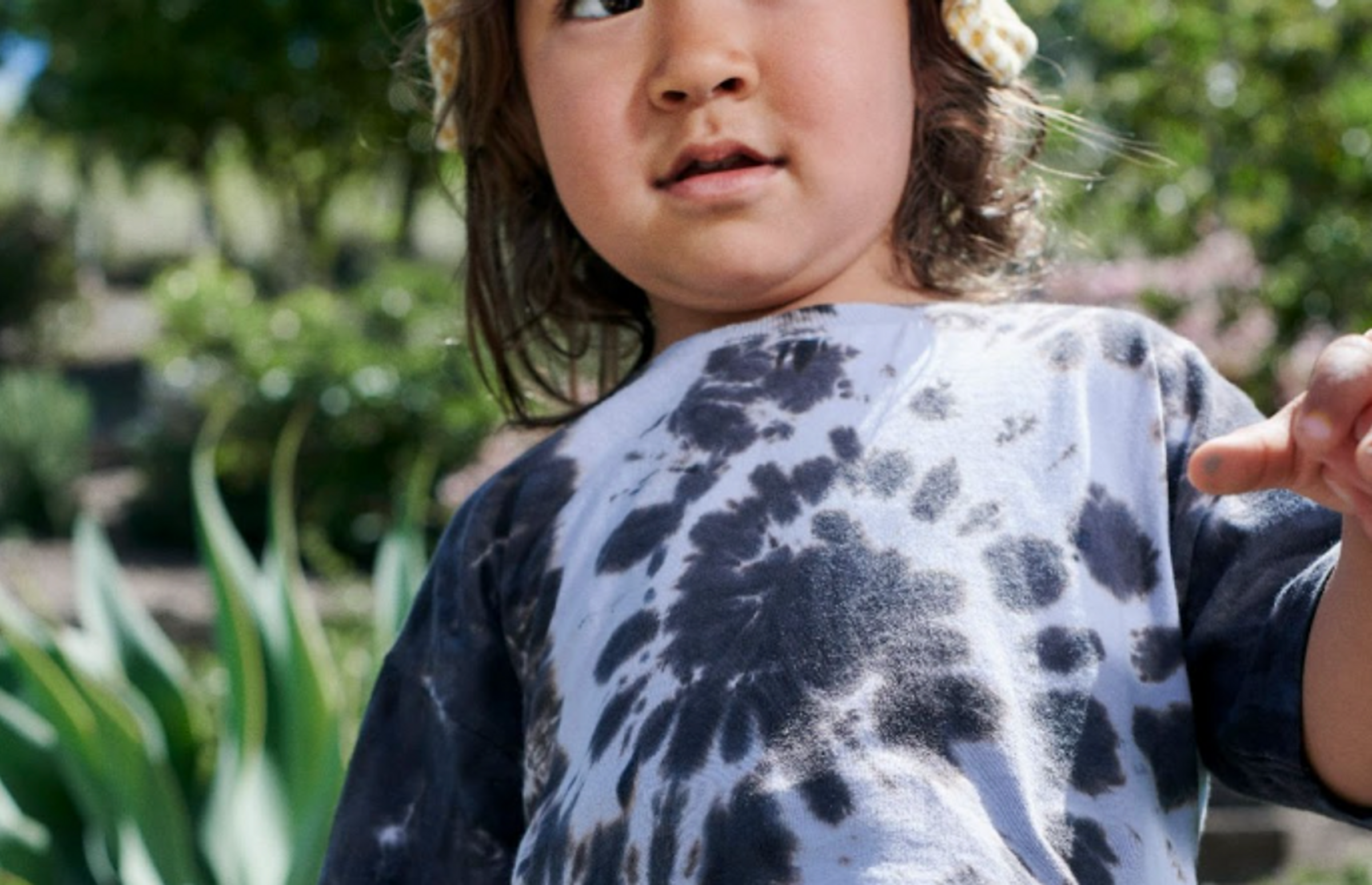a young boy is seen outside wearing a blue tie-dye shirt and Coterie diaper.