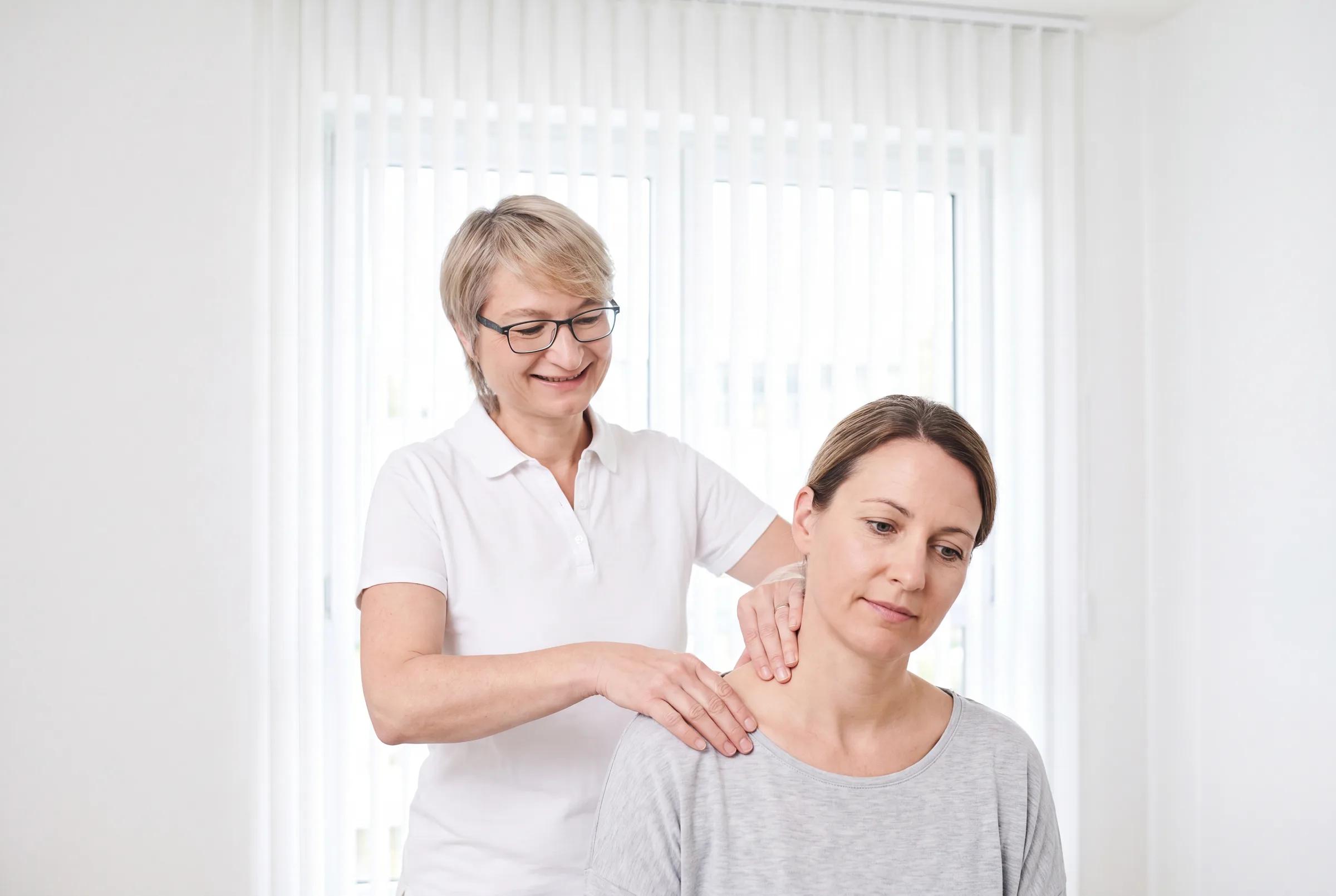 Ärztin behandelt bei der komplementären Orthopädie mit sanfter manueller Therapie den Nacken einer Patientin