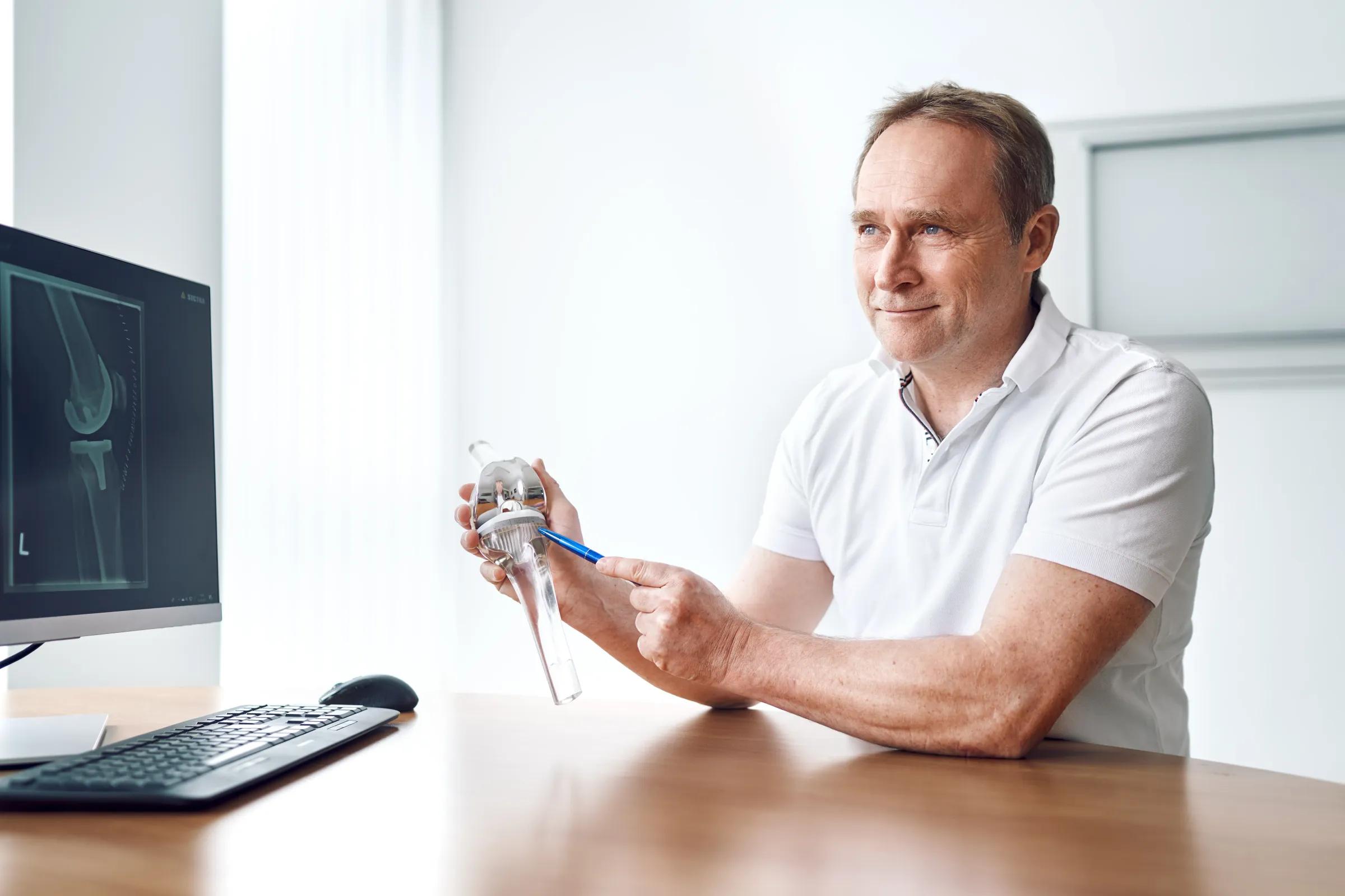 Arzt der Orthopädie MediaPark erklärt eine Knieprothese anhand eines Modells