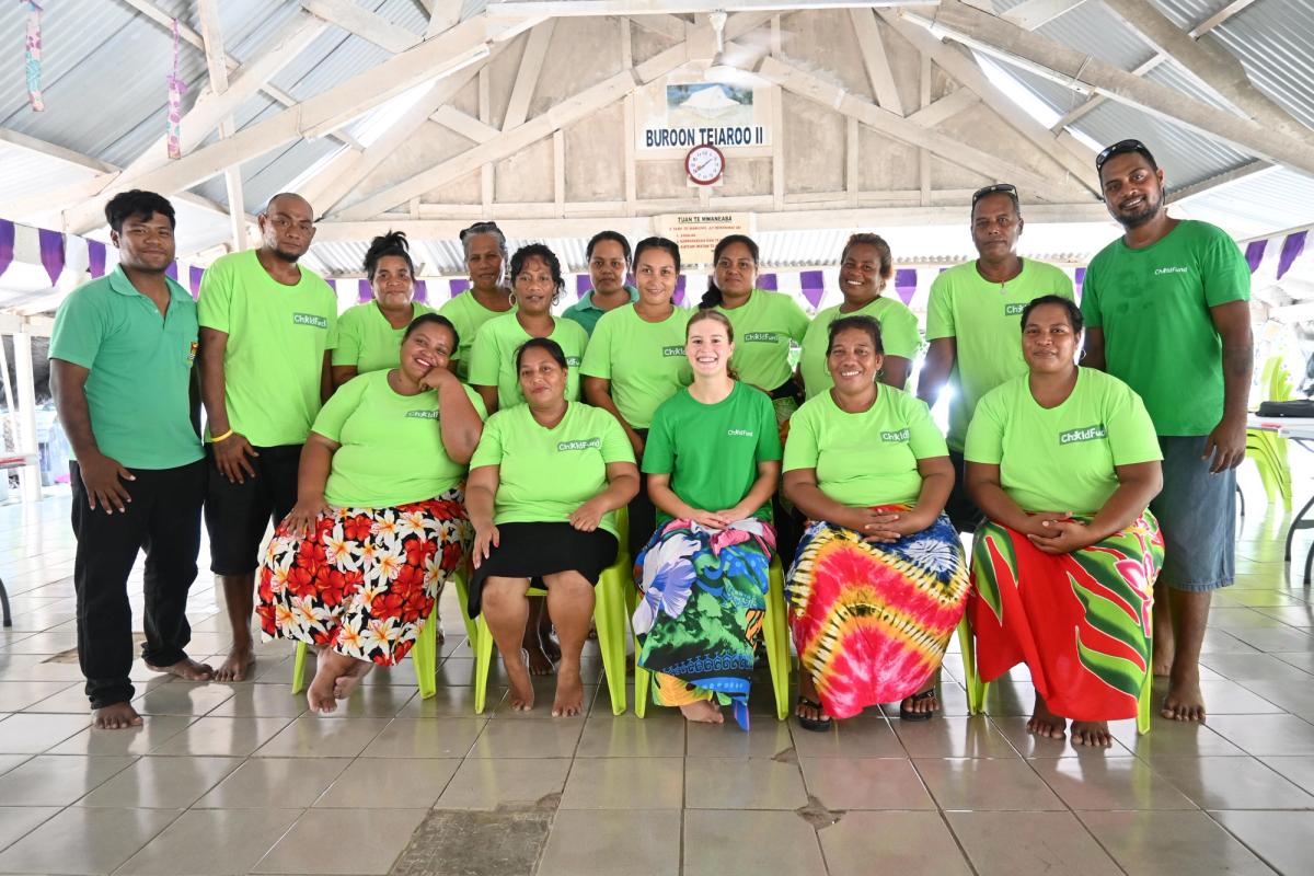 A group of people wearing a green uniform smile for the camera