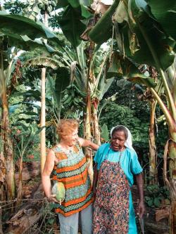 a woman in an apron holds a mango next to another woman