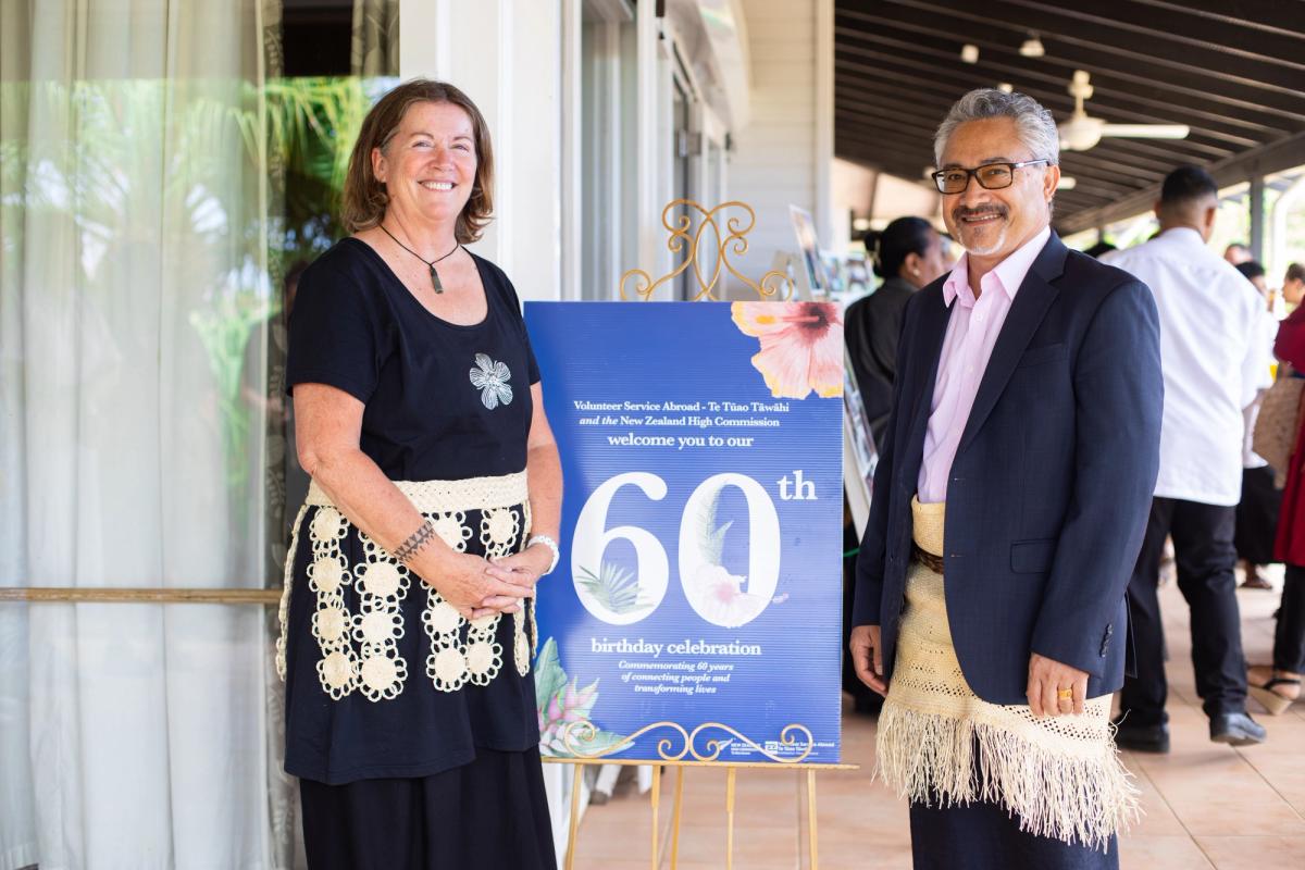A woman and man stand next to a banner and smile for the camera A woman and man stand next to a banner and smile for the camera