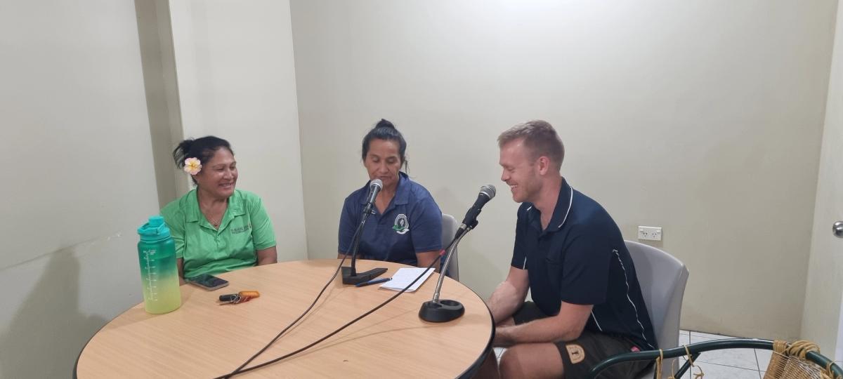Three people seated around a table speaking into microphones