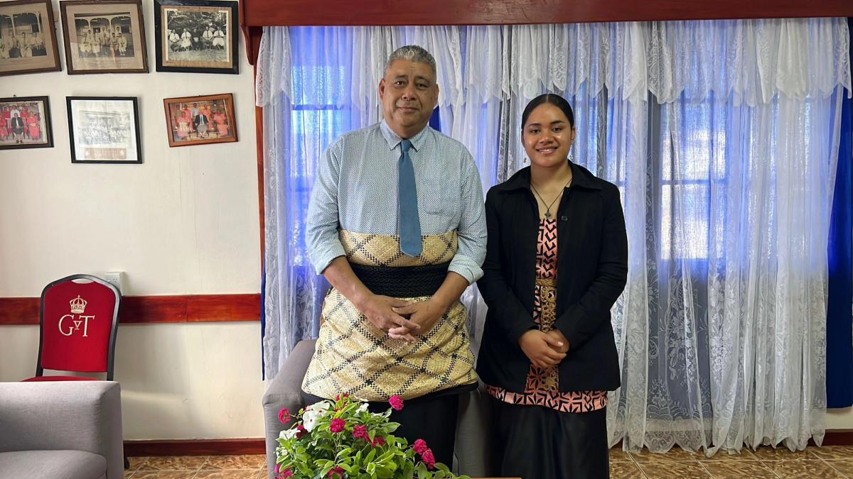 A man and young woman stand side by side and smile for the camera A man and young woman stand side by side and smile for the camera