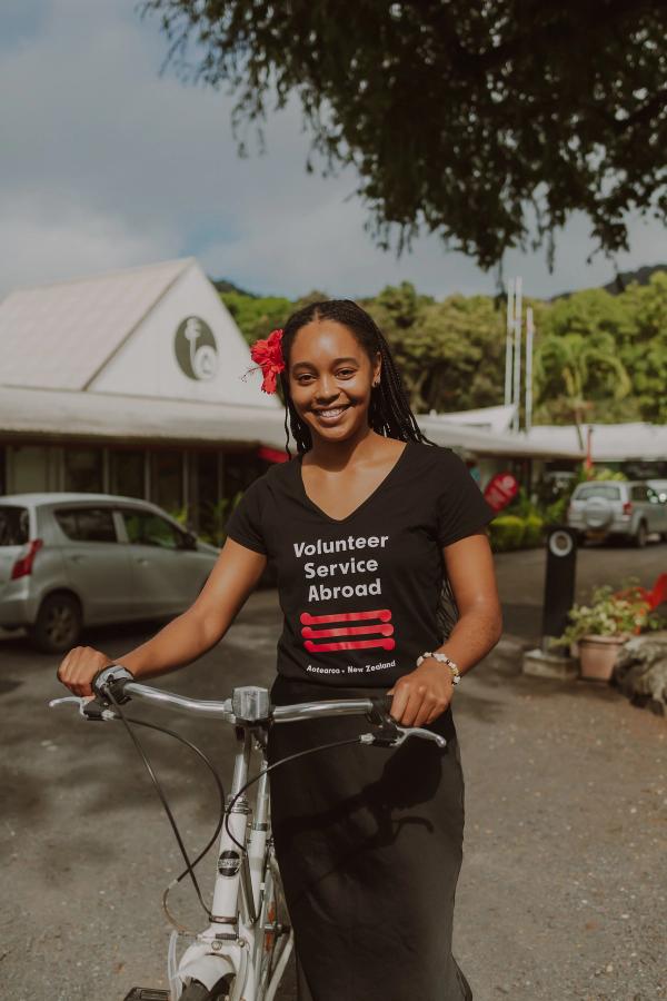 Volunteer Savannah stands with a bike and smiles for the camera