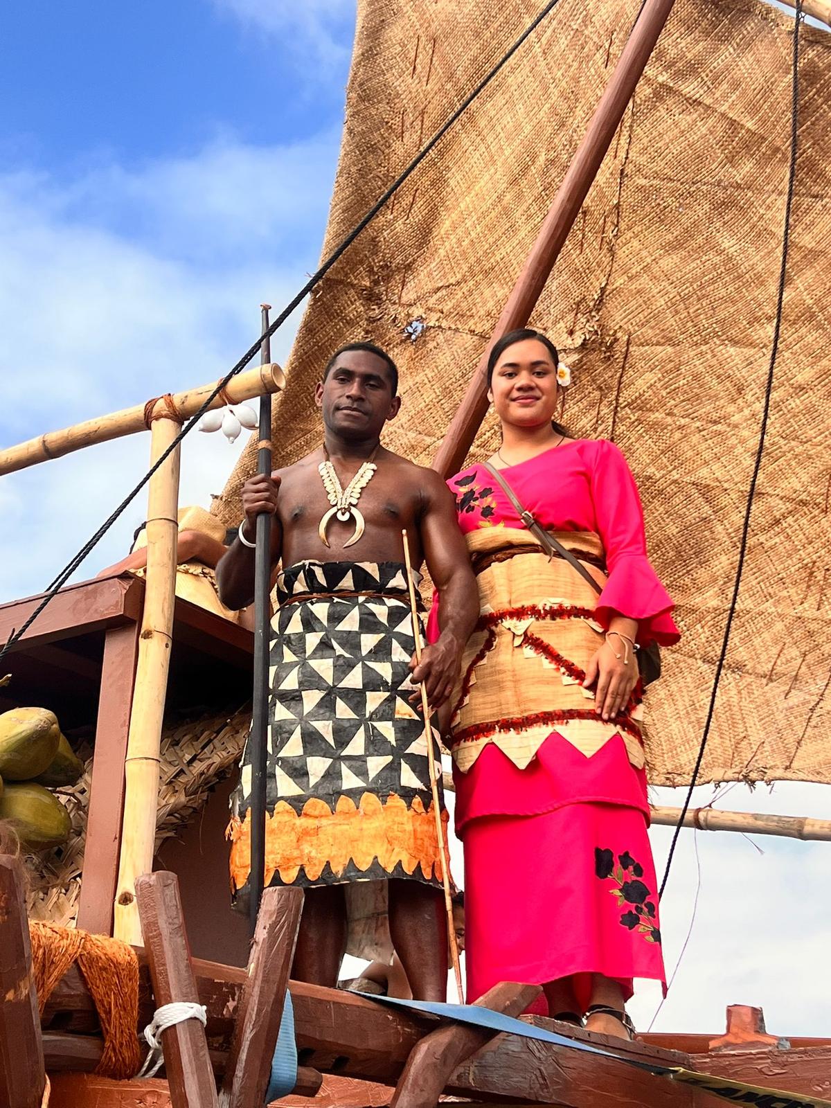 A young man and young woman in cultural attire smiling at the camera