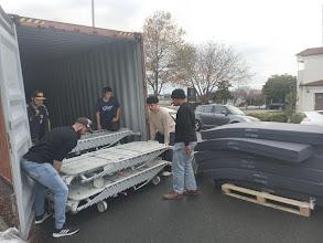 Volunteers work together to load some beds into a shipping container Volunteers work together to load some beds into a shipping container