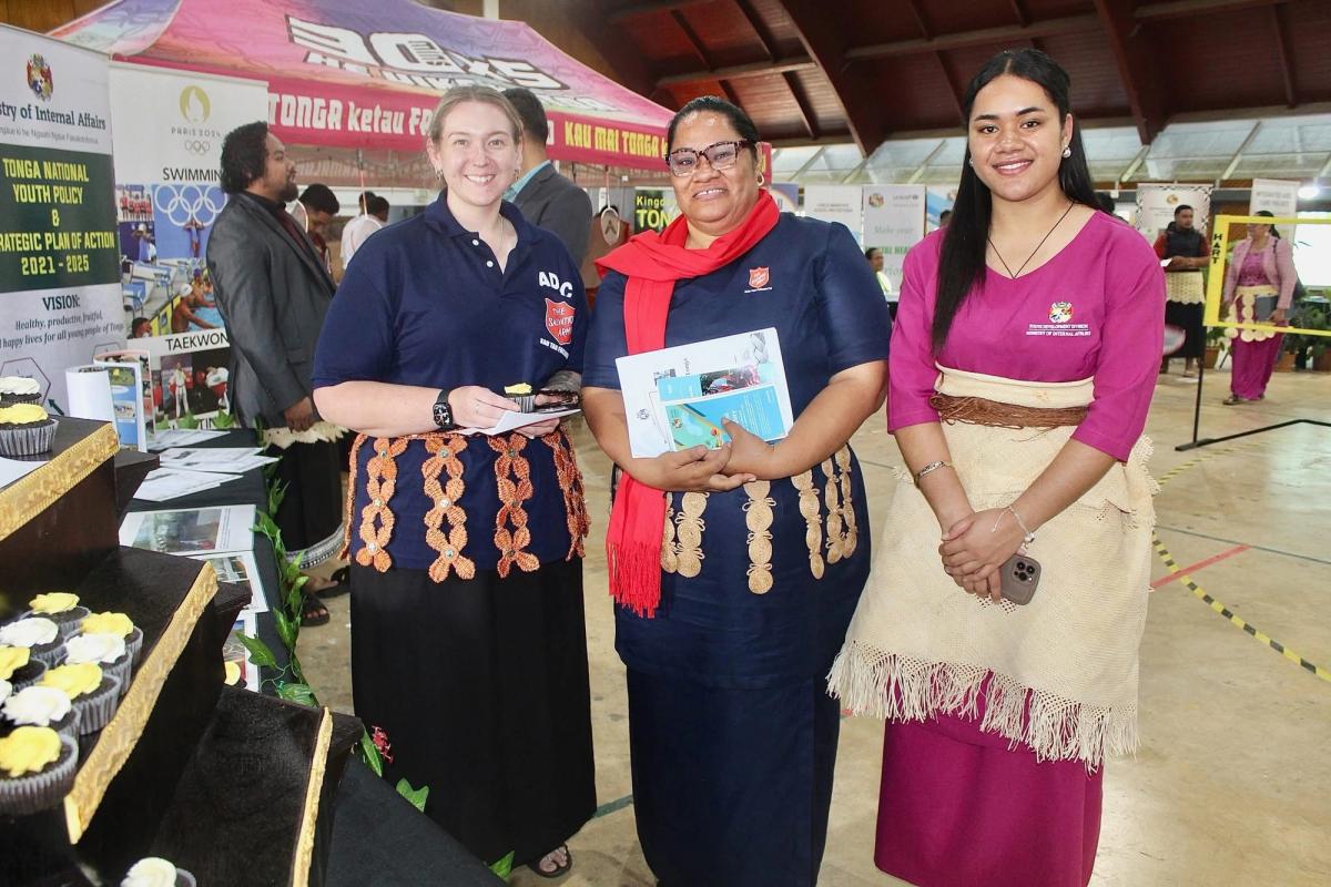 Three women standing by a stall and smiling for the camera