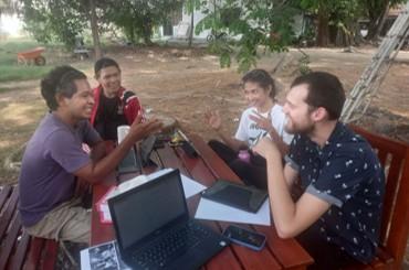A group of people seated around a table in discussion with laptops and papers in front of them. A group of people seated around a table in discussion with laptops and papers in front of them.