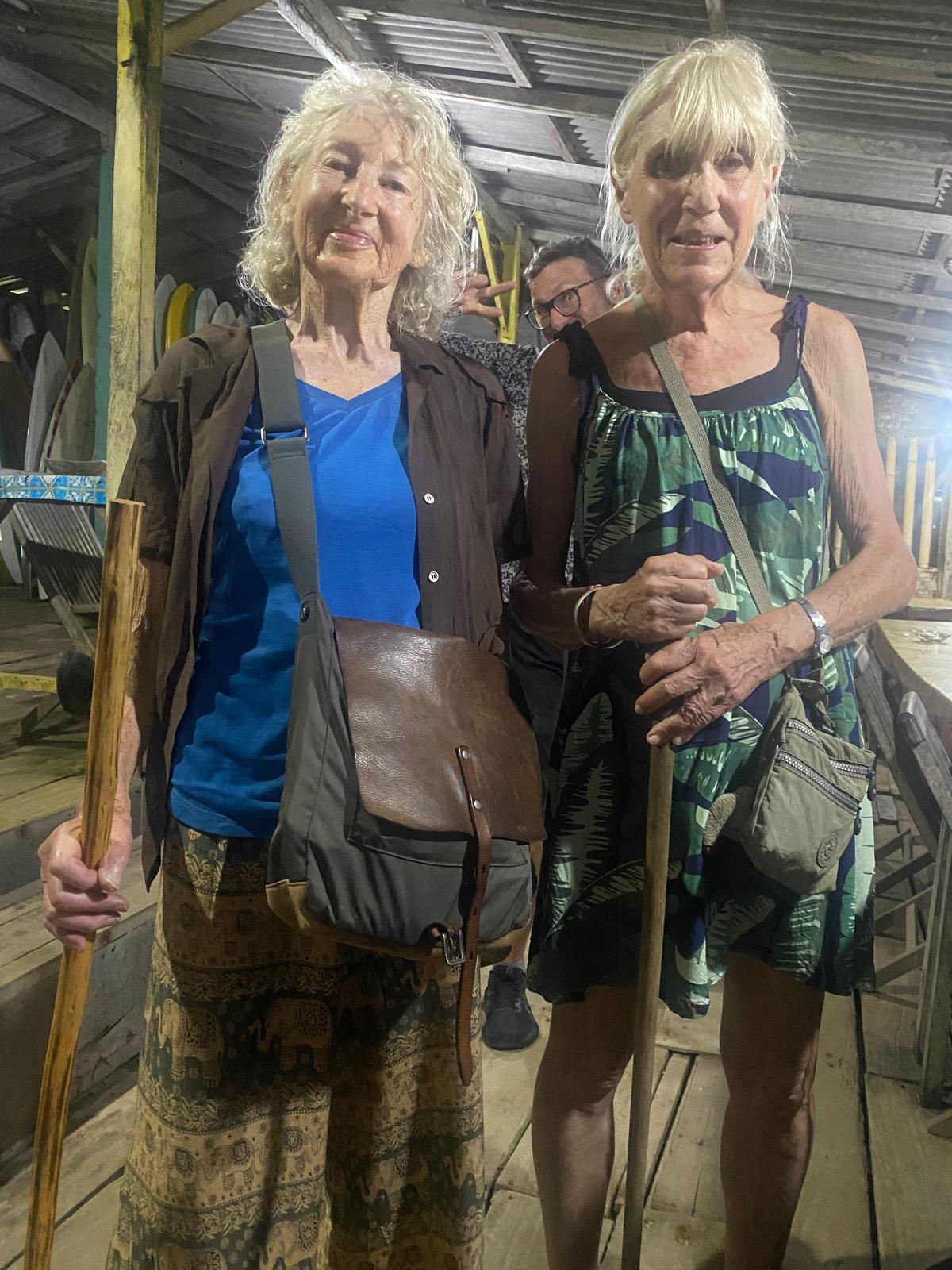 Two women holding walking sticks and bags.