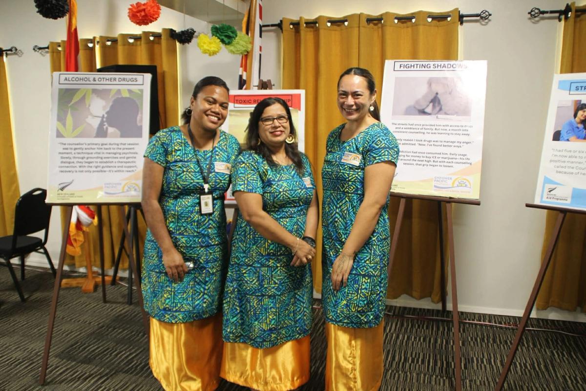 Three women smiling for the camera in front of display boards