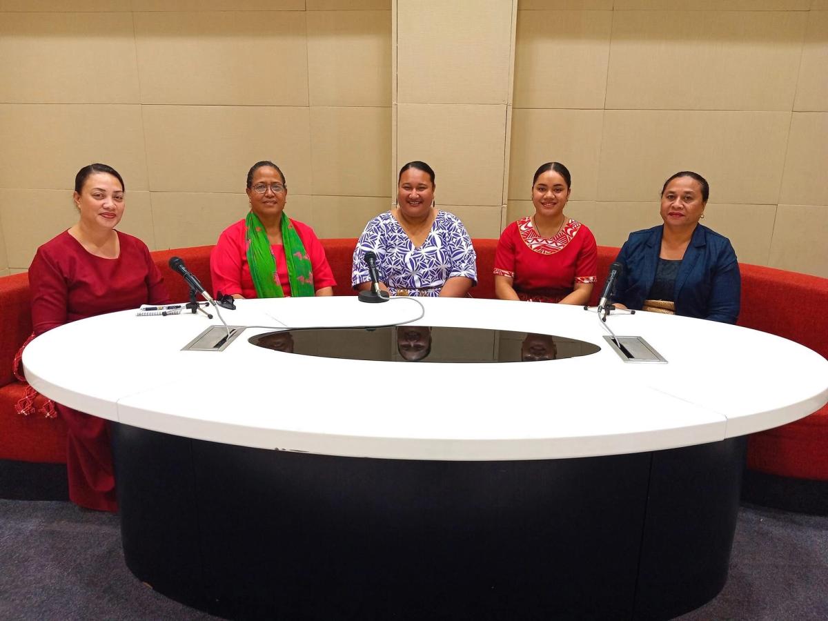 A group of women seated around a circular table and smiling at the camera