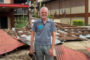 a man is standing in front of a pile of roofs . a man is standing in front of a pile of roofs .