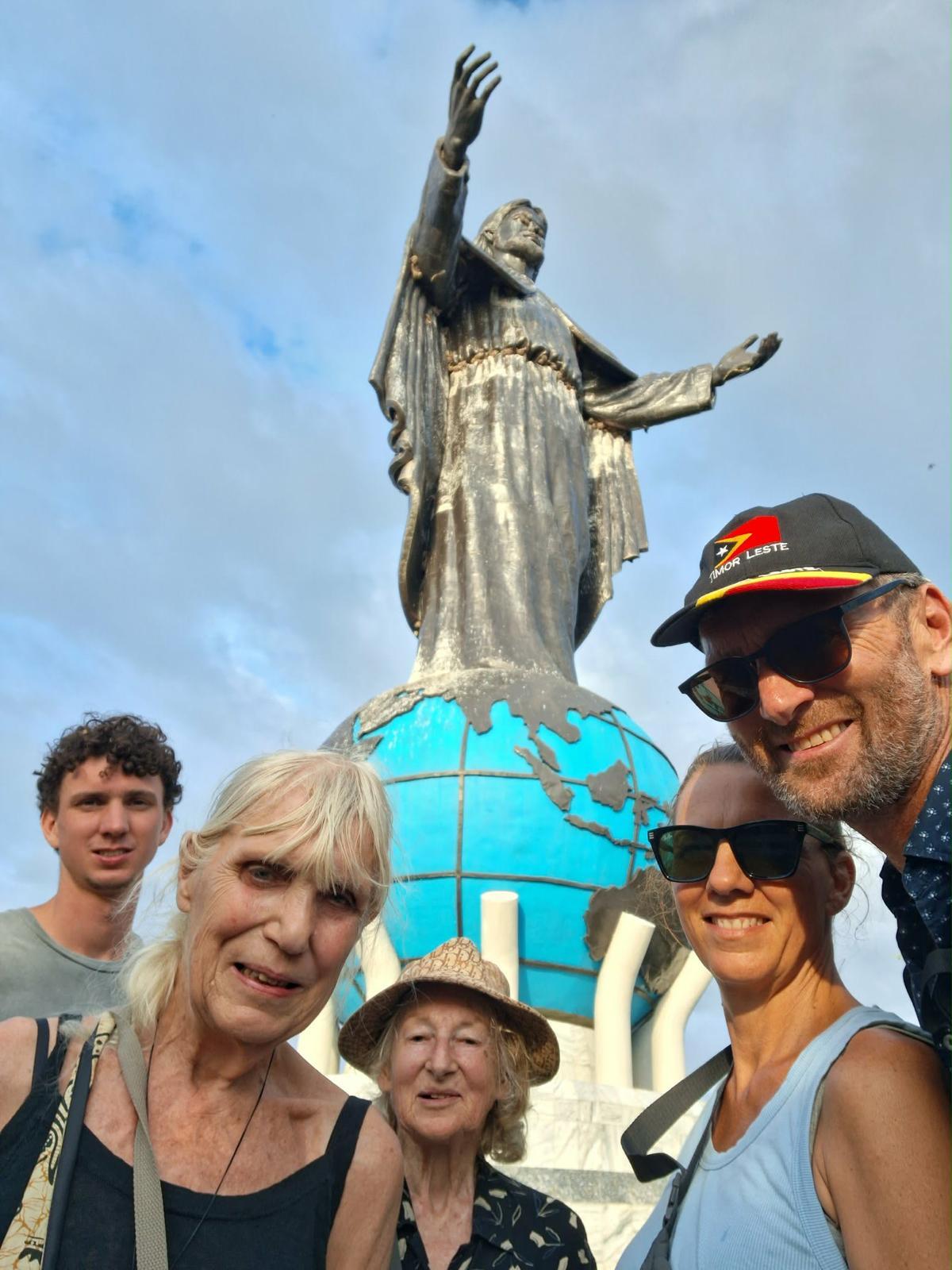 A family of five smile for the camera in front of a statue of Jesus. A family of five smile for the camera in front of a statue of Jesus.