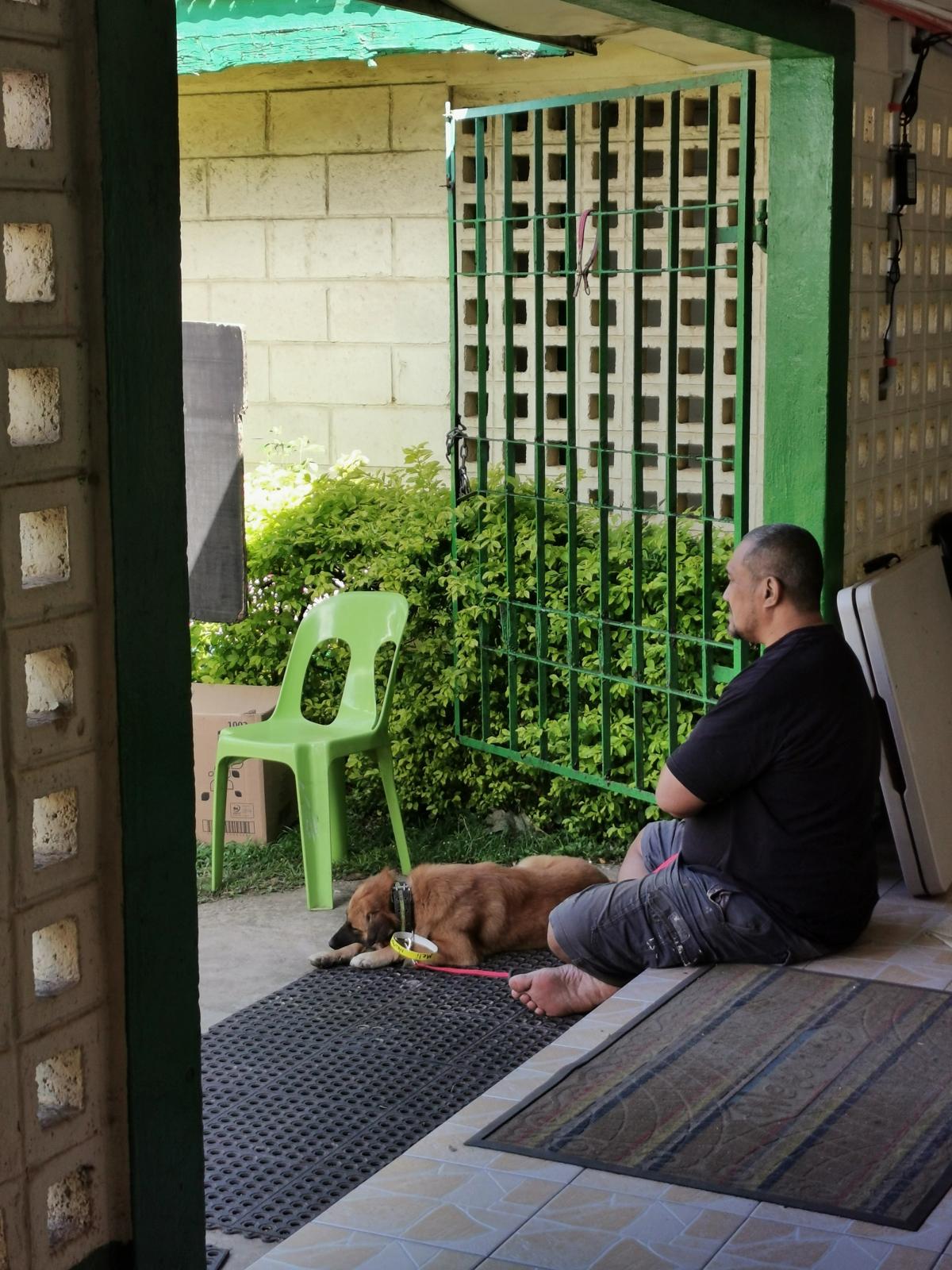 A man sits on the ground with his dog laying at his feet A man sits on the ground with his dog laying at his feet