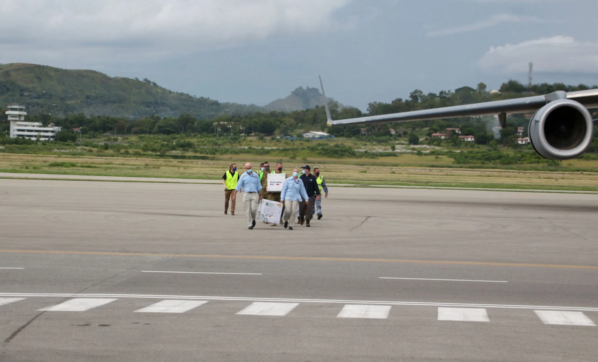 A group of people carrying boxes of aid on the tarmac A group of people carrying boxes of aid on the tarmac