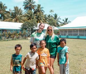 a group of children are posing for a picture with a woman in a green shirt . a group of children are posing for a picture with a woman in a green shirt .