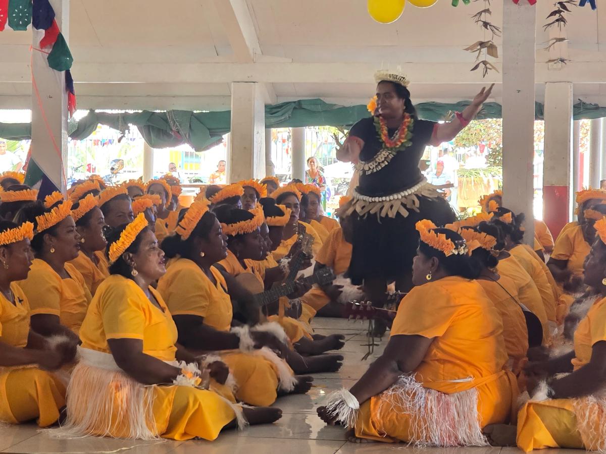 A group of women seated around a single woman standing and dancing