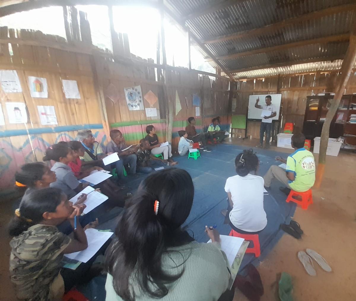 A group of teachers seated around a mat looking at a male who stands and teaches from the front of the room