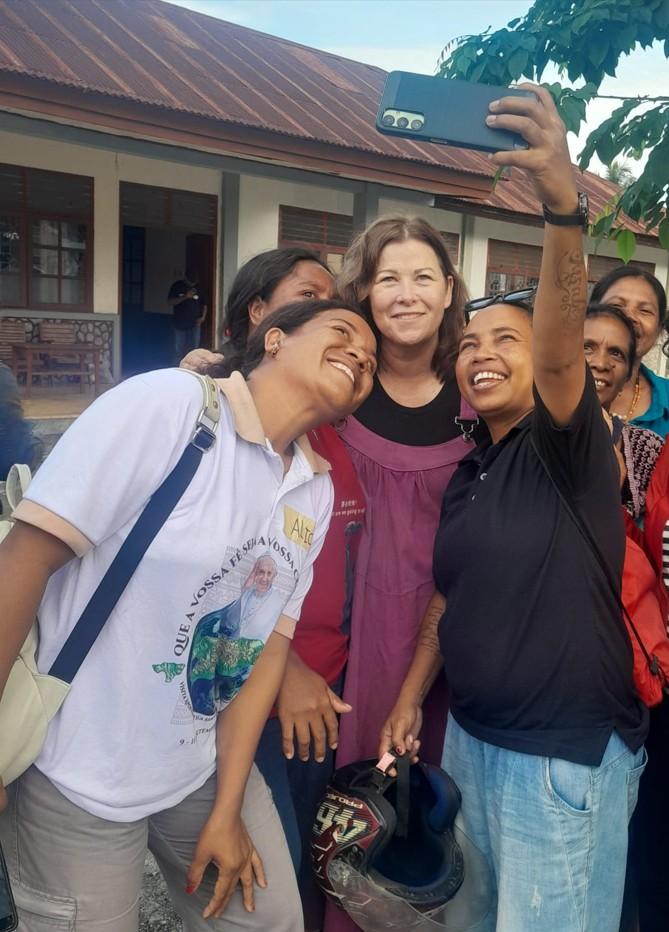 A group of women stand and smile for a selfie