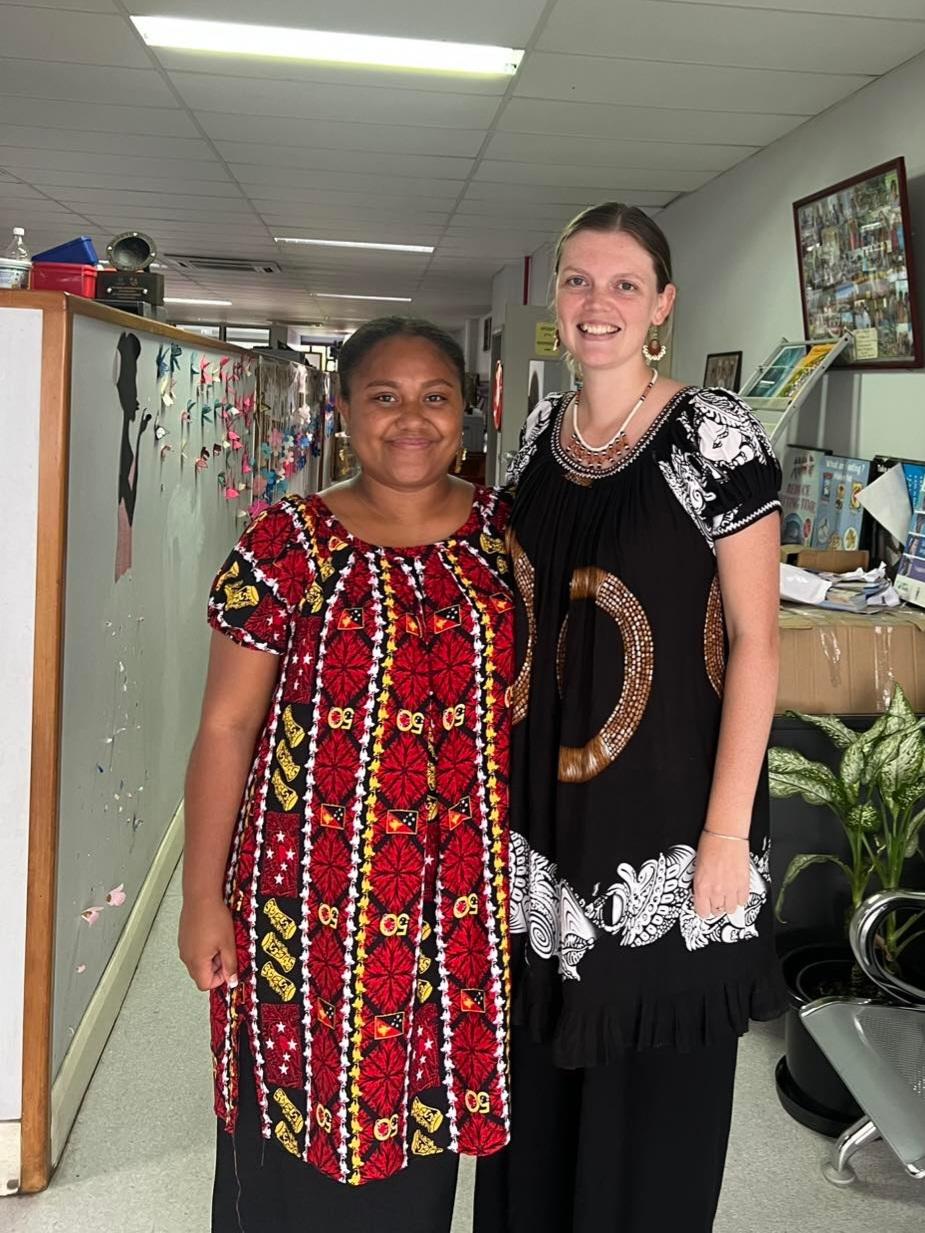 Two young women stand side by side and smile for the camera