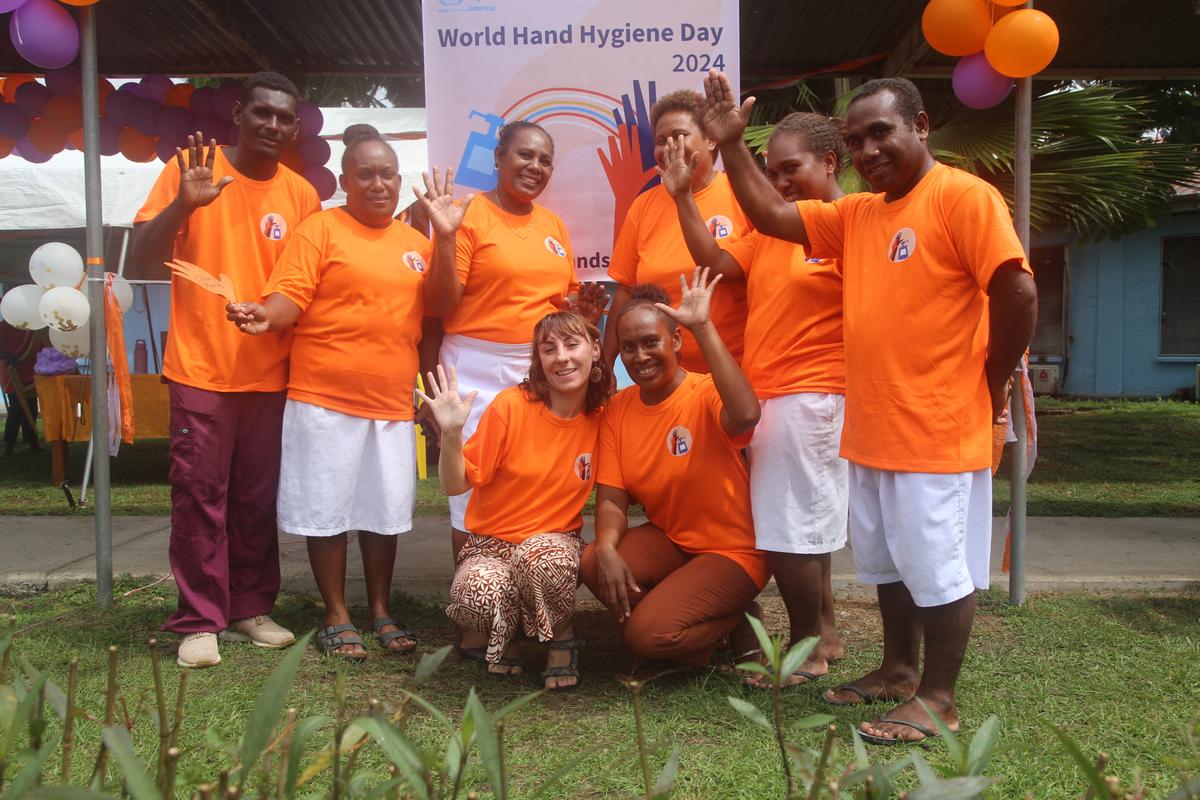 A group of people wearing orange and smiling for the camera