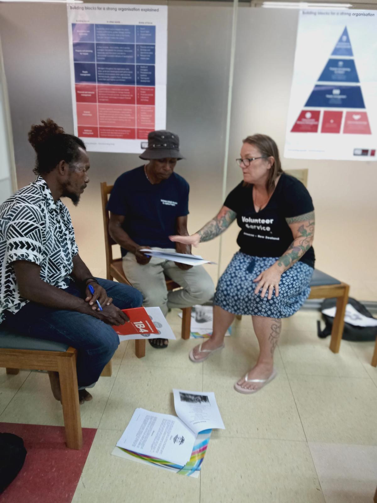 Three people seated on chairs and in discussion. Three people seated on chairs and in discussion.