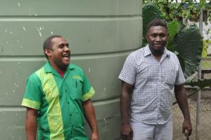 two men are standing next to each other in front of a green wall . two men are standing next to each other in front of a green wall .