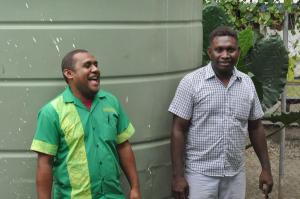 two men are standing next to each other in front of a green wall .