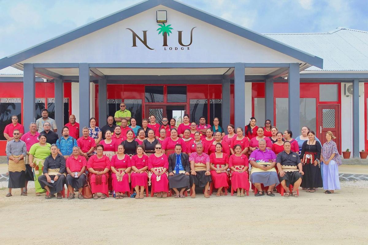 A large group of people seated in front of an open house and looking at the camera A large group of people seated in front of an open house and looking at the camera