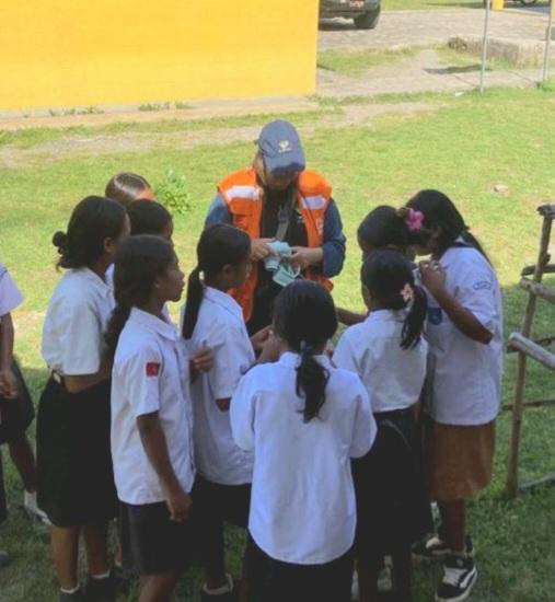 A group of students huddle around a woman with a camera.