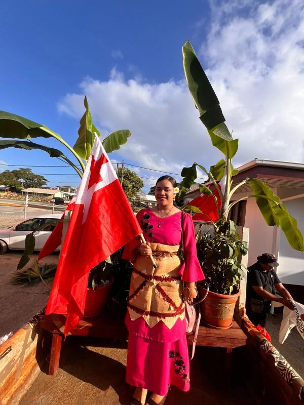 A young woman smiles and holds the Tongan flag A young woman smiles and holds the Tongan flag