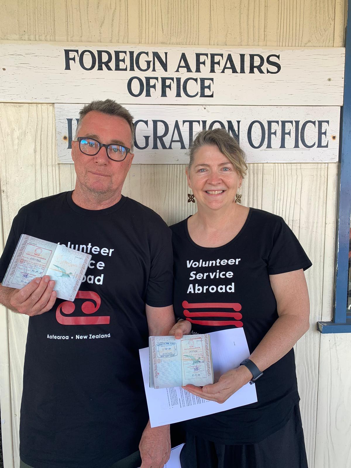 A couple smiling for the camera outside of the immigration office holding their passports A couple smiling for the camera outside of the immigration office holding their passports