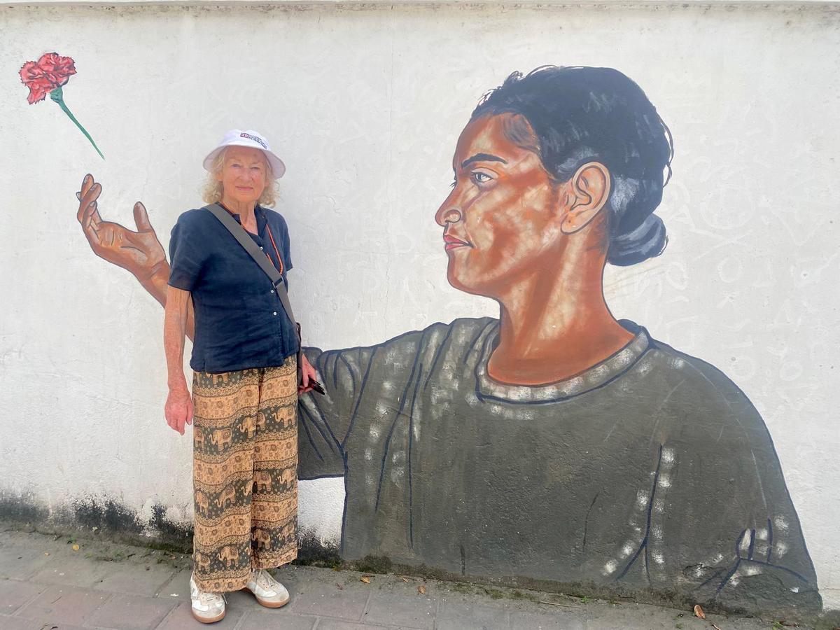 A woman stands in front of a painted mural and smiles for the camera.