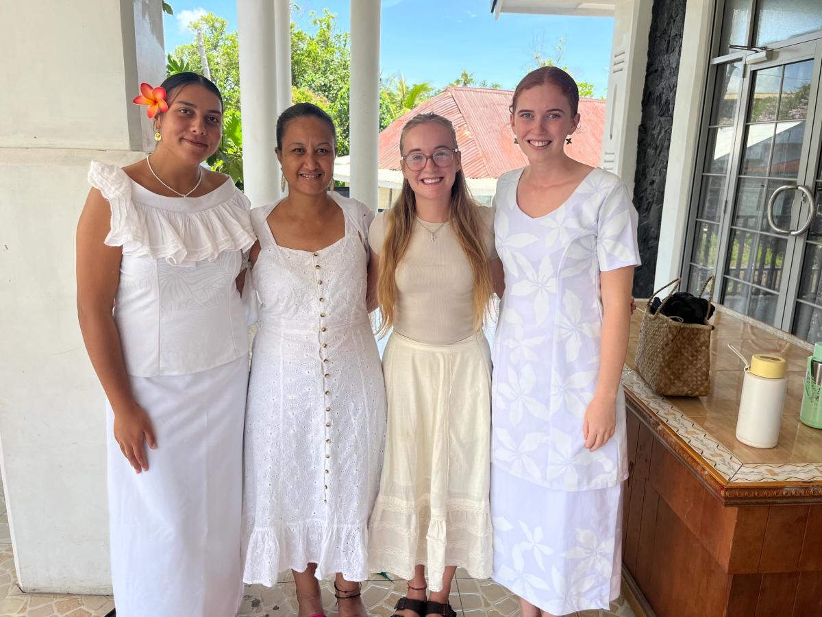 A group of women dressed in white formal attire smiling for the camera A group of women dressed in white formal attire smiling for the camera