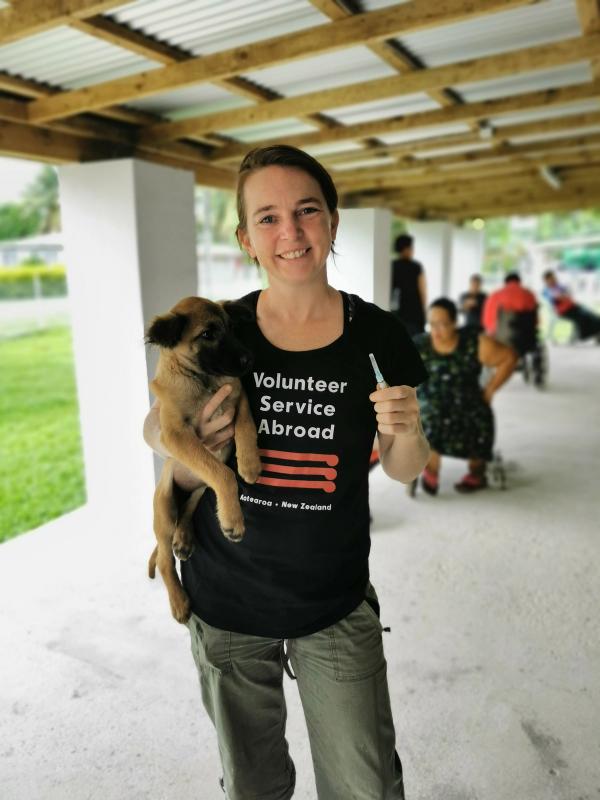A volunteer vet holds a dog and smiles for the camera A volunteer vet holds a dog and smiles for the camera