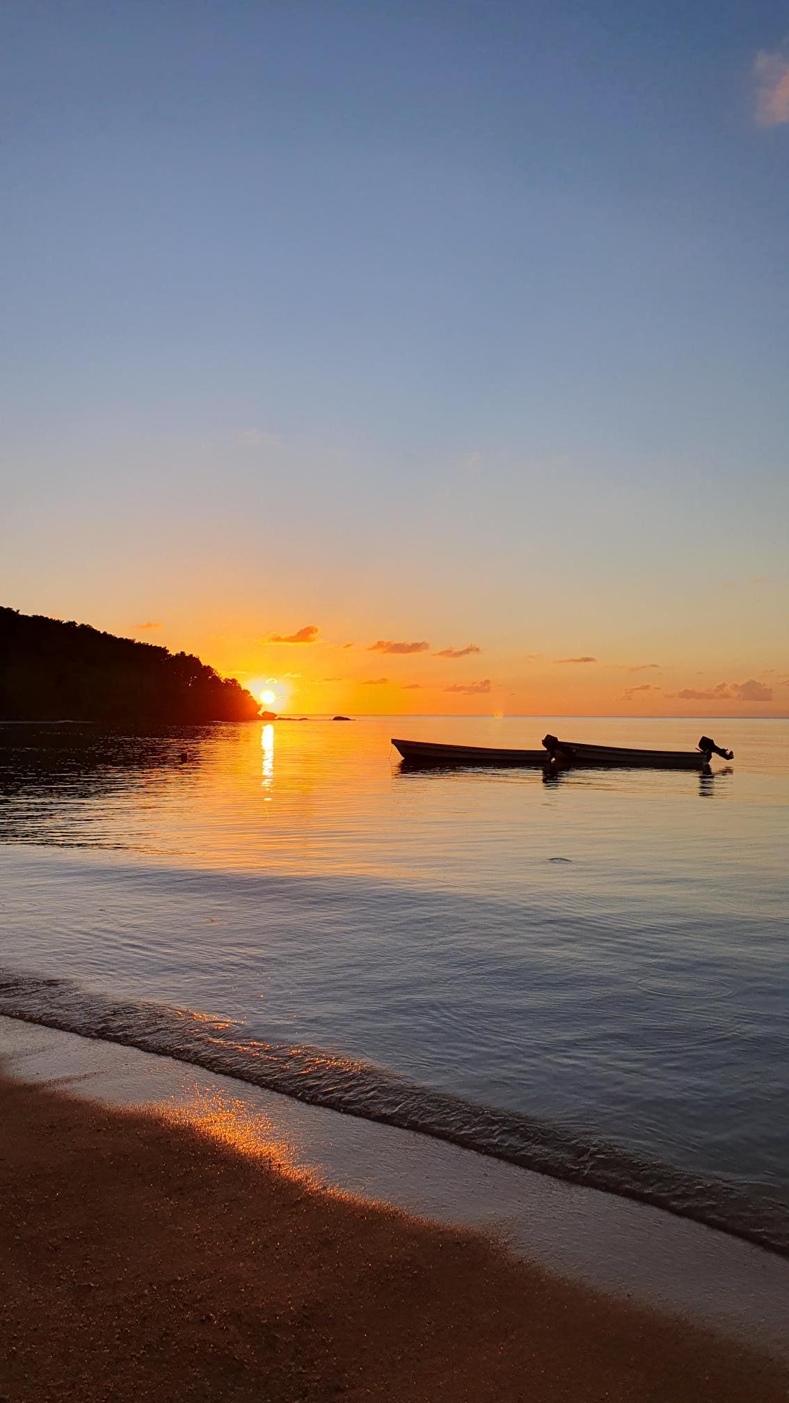 A scenic coastal image of the sunset with a canoe in the foreground
