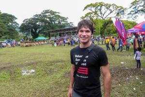 a man wearing a black volunteer shirt is standing in a field .