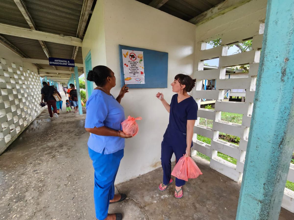 Two nurses look at an informational poster on the wall Two nurses look at an informational poster on the wall